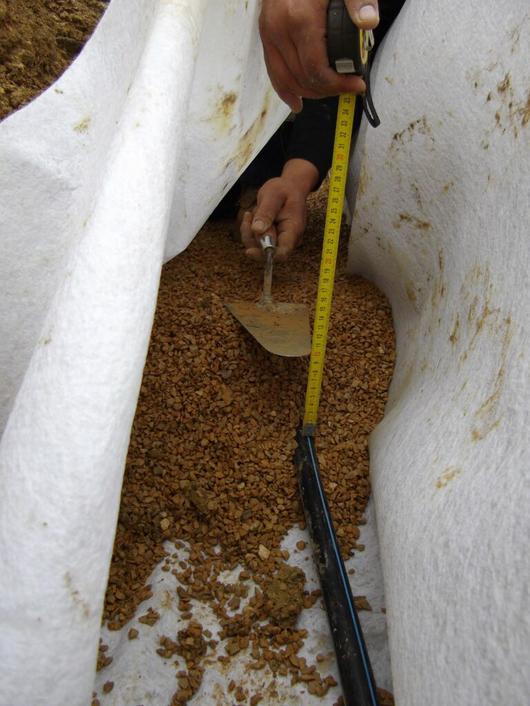 ESTP Terrassement - Mise en place du gravier 2/4 pour enrober le tuyau de refoulement de la tranchée d’infiltration.